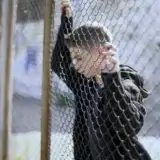Teen standing by a fence, symbolizing hope and resilience of Connecticut survivors overcoming institutional abuse.