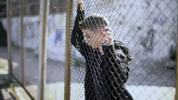 Teen standing by a fence, symbolizing hope and resilience of Connecticut survivors overcoming institutional abuse.